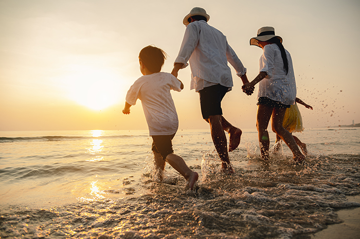 Happy family consisting of a father, mother,son and daughter having fun playing beach in summer vacation on the beach.