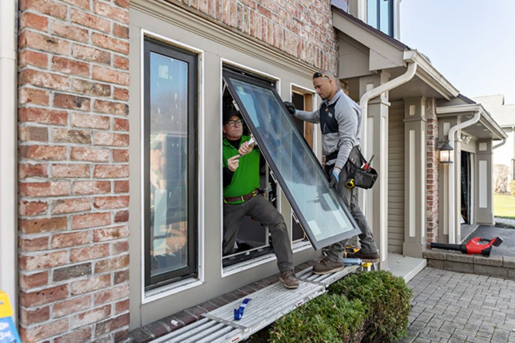 Two window installers installing Renewal By Anderson awning and picture windows