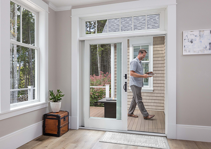 Man walking up to patio door with BBQ in hand