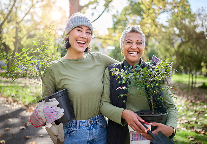 Portrait, flowers and women volunteering in park for community, outreach or programme together. Environment, charity and friends volunteer in forest for gardening project, happy and smile in nature.