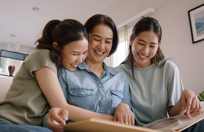Recall the past life memories Happy time Mother's day grown up kid child joy fun look at old retro photo album with mature mum. Asia adult people middle age mom smile enjoy relax sitting at home sofa.