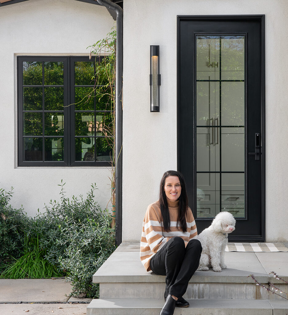 Laurie March sitting on front porch with dog with Renewal By Andersen Windows and Entry door behind